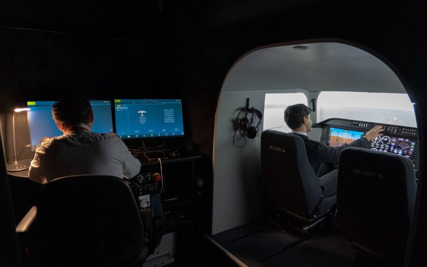 Instructeur au pupitre du simulateur ALSIM AL250 pendant qu'un élève pilote la séance
