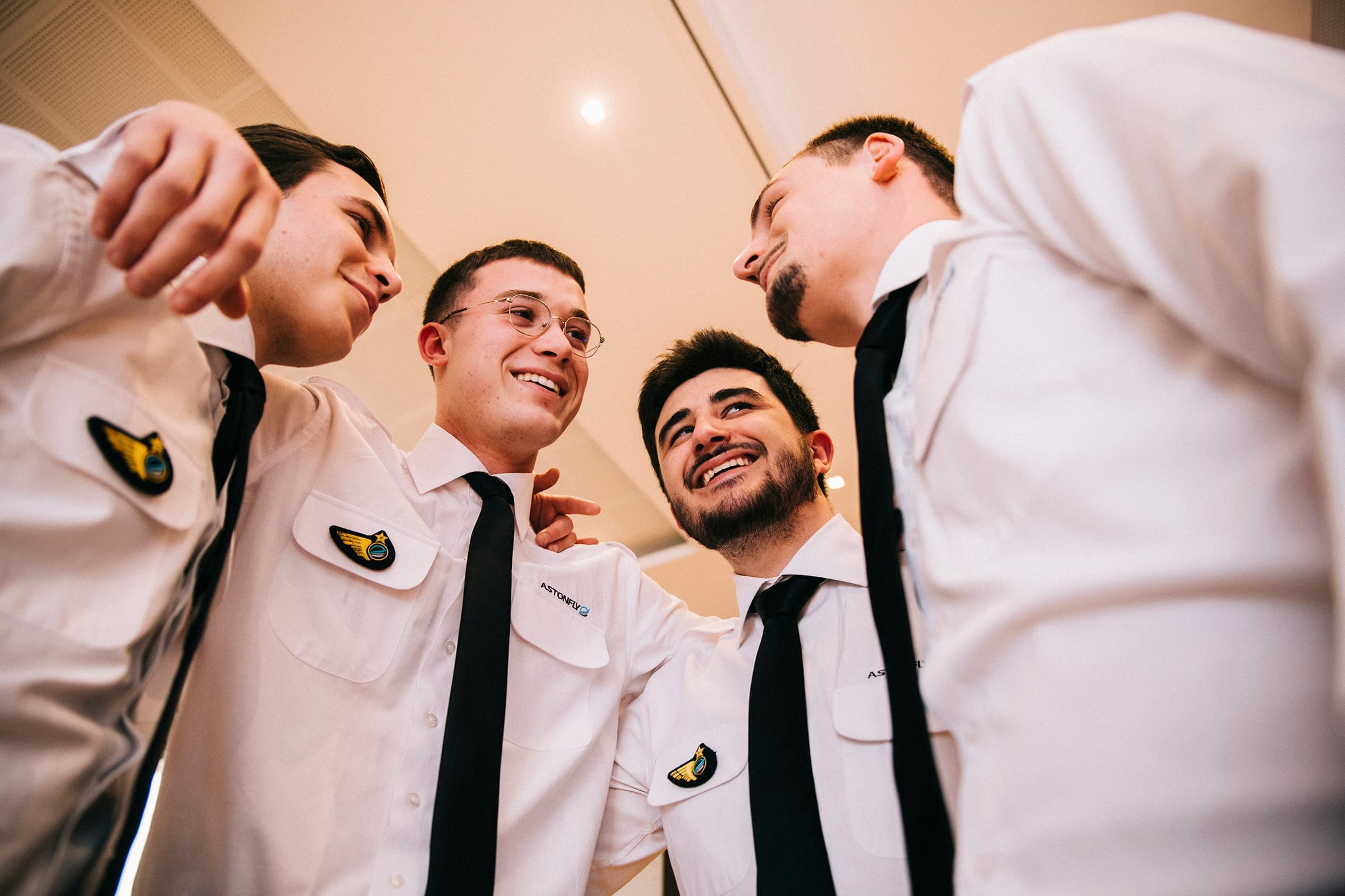 Quatre élèves pilotes Astonfly en uniforme, réunis en cercle et souriants